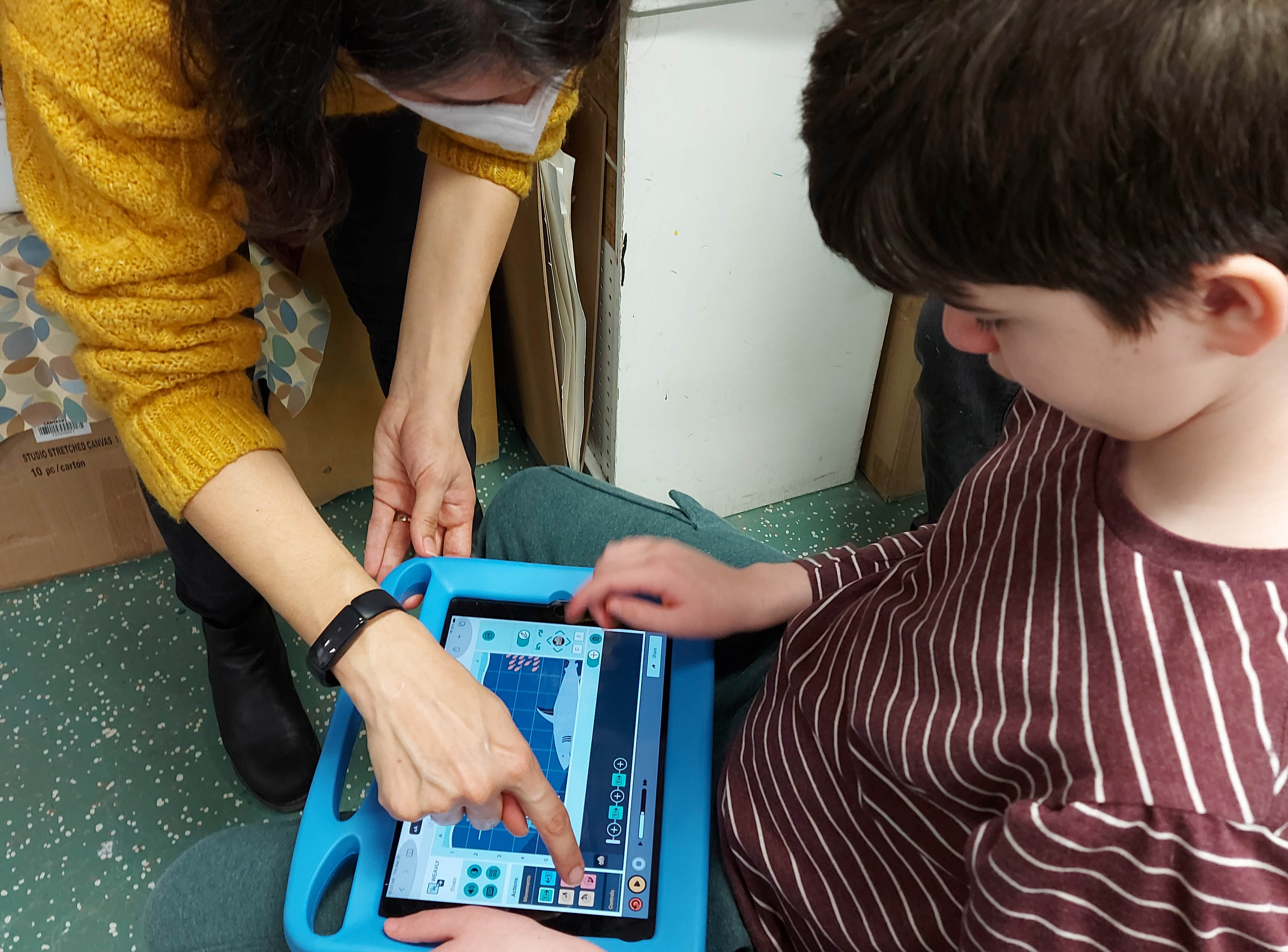 Facilitator showing new items on the Weavly coding environment to a child